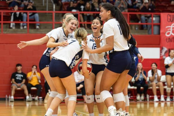 Senior Ava Annunzio (left), junior Sophia Fuentes (middle), and others celebrate freshman Clair Bolton (number seven) on her kill. 